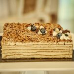A delectable layered cake topped with blueberries and nuts, perfect for dessert enthusiasts.