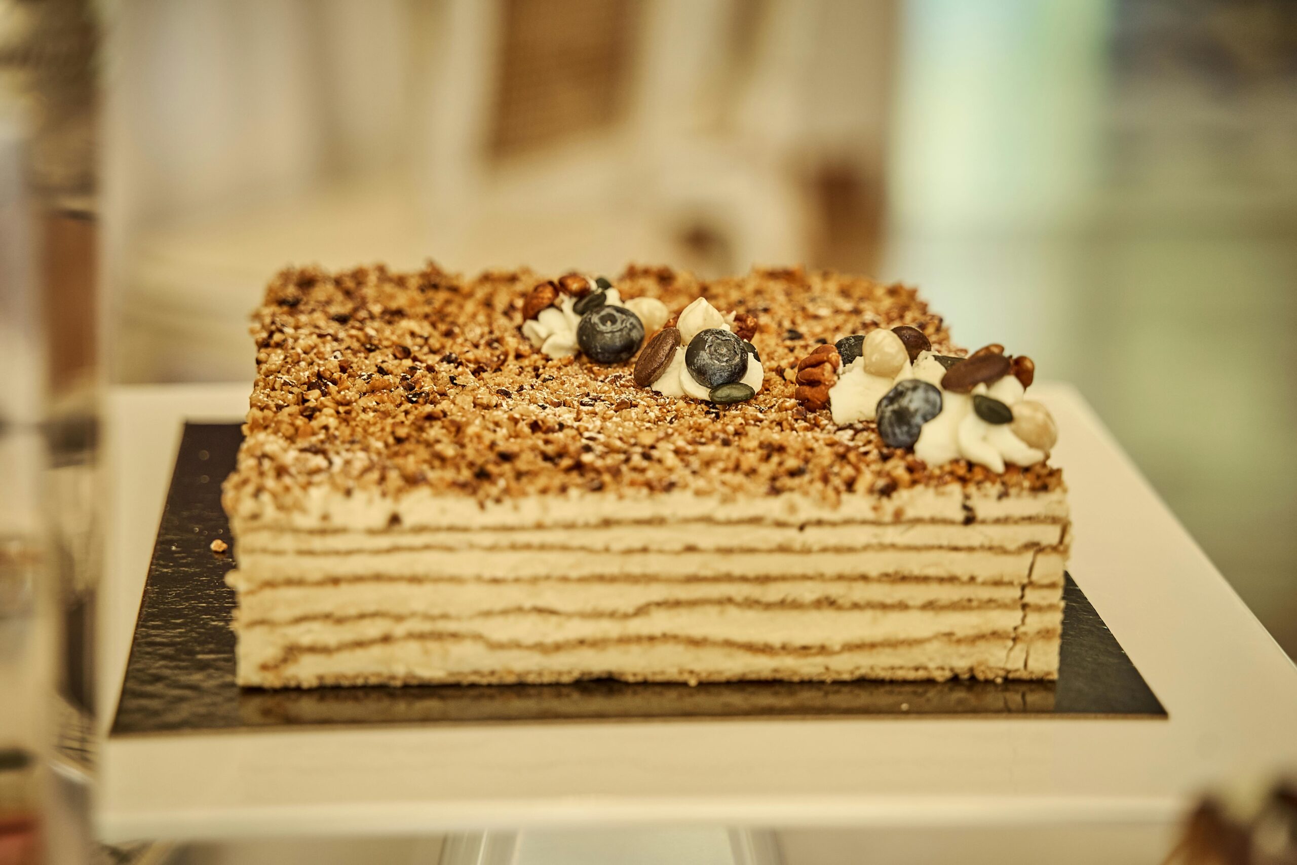 pexels photo 13218485 13218485 A delectable layered cake topped with blueberries and nuts, perfect for dessert enthusiasts.