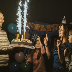 A family celebrating a birthday with a sparkling cake and joyful moments indoors.