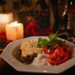 Cozy dinner setup with a gourmet meal, candles, and wine for a romantic evening.