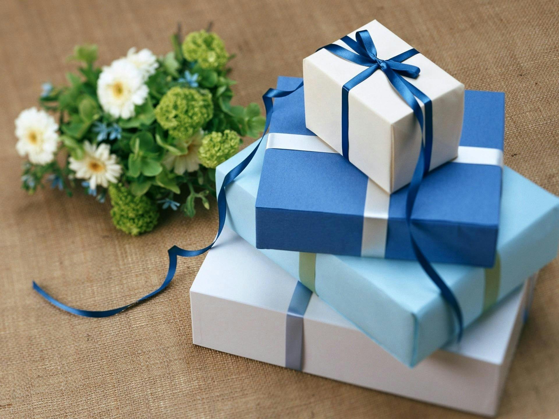pexels photo 264787 264787 Three beautifully wrapped gift boxes with blue ribbons arranged beside a floral bouquet.