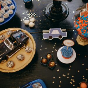 Vibrant birthday table setup with cupcakes, toy car, and candy for a festive celebration.