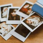 A collection of instant photo prints scattered on a wooden table, featuring personal moments.