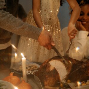 A family enjoys a cozy Thanksgiving dinner with a turkey centerpiece and candlelight ambiance.