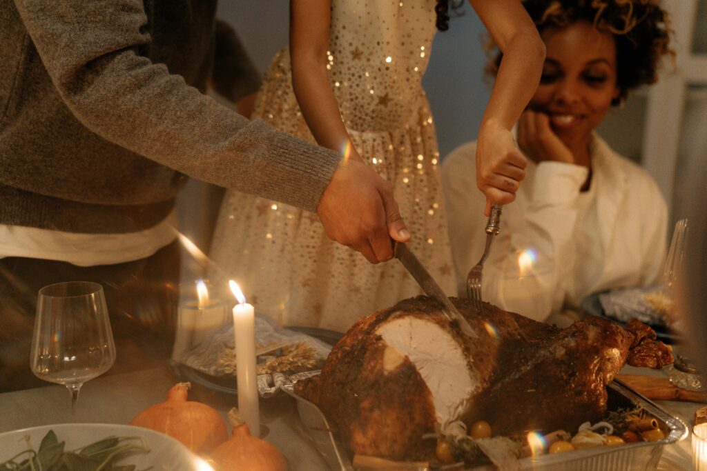A family enjoys a cozy Thanksgiving dinner with a turkey centerpiece and candlelight ambiance.