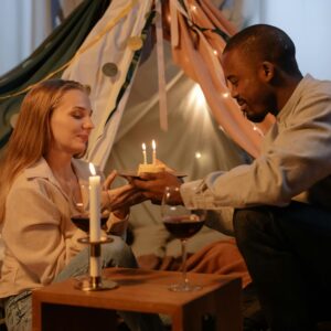 A couple celebrating a birthday indoors with candles and wine, creating a romantic atmosphere.