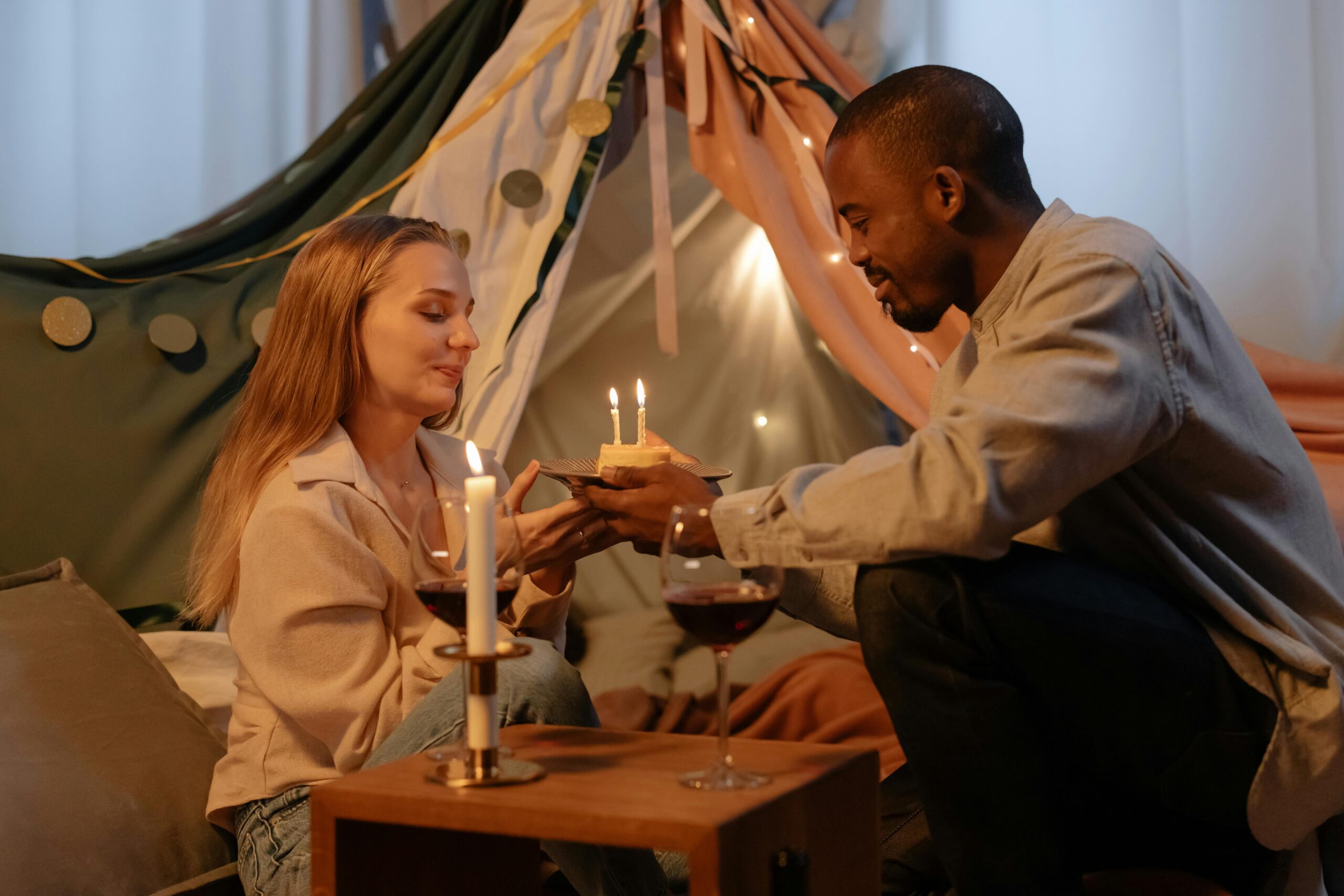 pexels photo 6670580 6670580 A couple celebrating a birthday indoors with candles and wine, creating a romantic atmosphere.