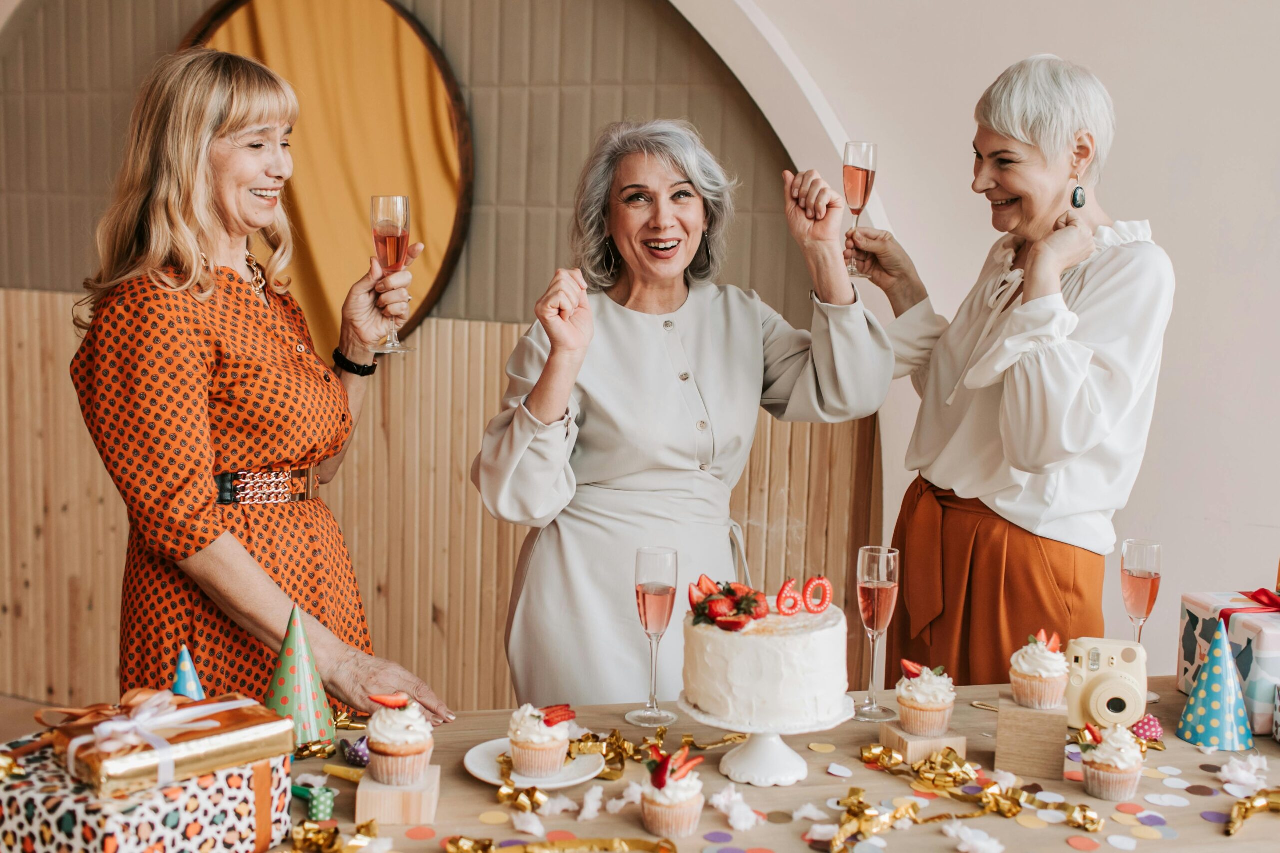 pexels photo 7561326 7561326 Three senior women celebrating a birthday with cake and champagne indoors.