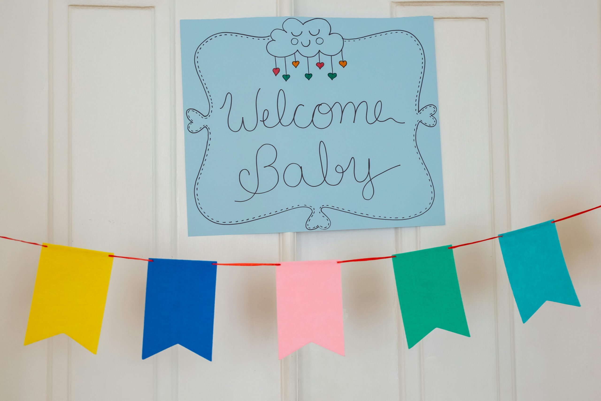 pexels photo 7802482 7802482 Cheerful baby shower decorations with colorful banner and welcome sign displayed indoors.