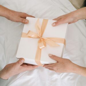 Hands exchanging a beautifully wrapped gift box, symbolizing celebration and sharing.