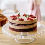 Delicious chocolate layered cake with berries on a glass stand indoors, perfect for celebrations.
