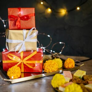 Colorful wrapped presents on a tray adorned with lights and marigold flowers for Diwali celebration.